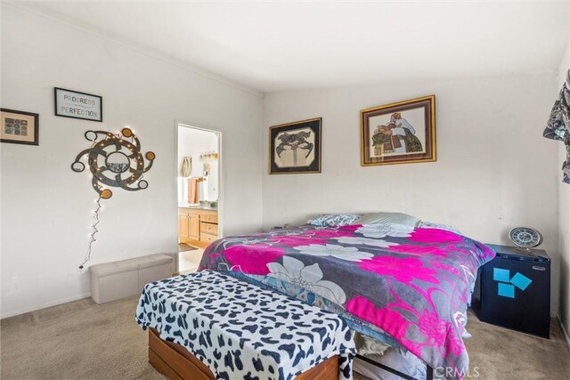 bedroom featuring light colored carpet and ensuite bathroom