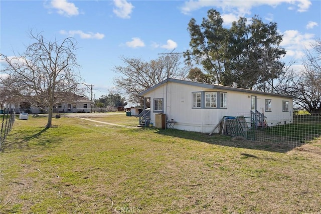 view of side of home featuring fence and a lawn