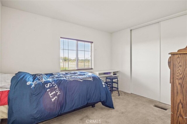 bedroom with visible vents, a closet, and light colored carpet