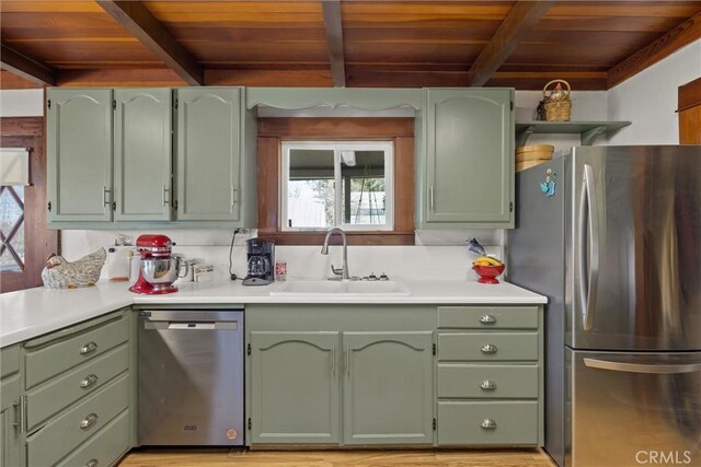 kitchen featuring green cabinets, stainless steel appliances, a sink, and light countertops