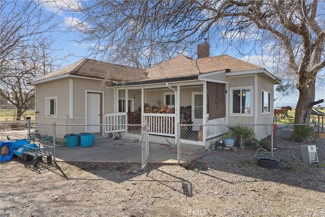 view of front of home featuring fence private yard, a shingled roof, a chimney, and a porch