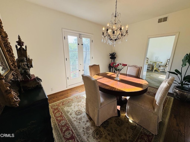 dining space featuring wood finished floors, a chandelier, and visible vents