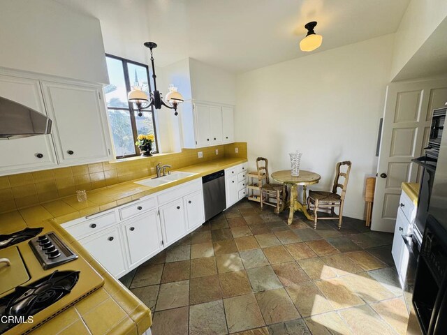 kitchen with tile counters, stone tile floors, dishwasher, a sink, and decorative backsplash