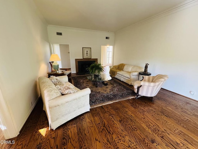 living room featuring wood finished floors, visible vents, crown molding, baseboards, and a fireplace