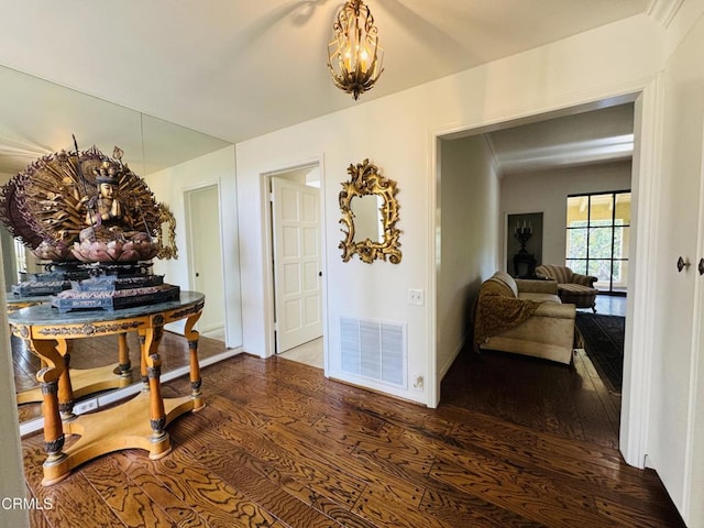 hallway featuring wood finished floors, visible vents, and a notable chandelier