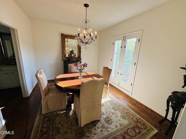 dining area with baseboards, a chandelier, wood finished floors, and french doors