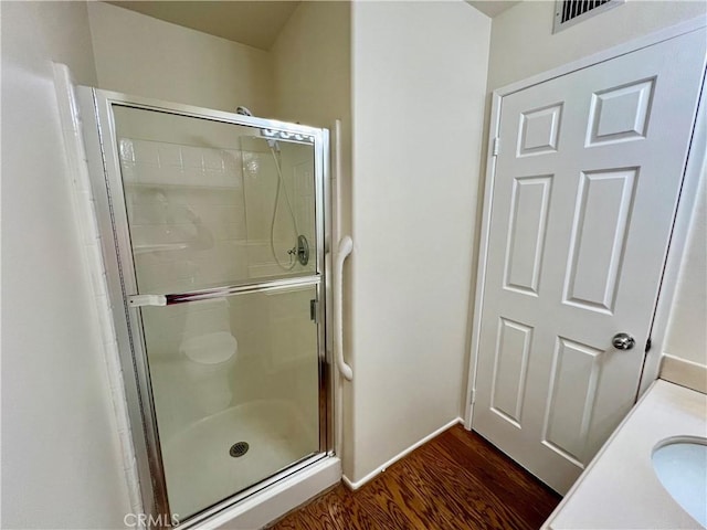 bathroom with walk in shower, wood-type flooring, and vanity