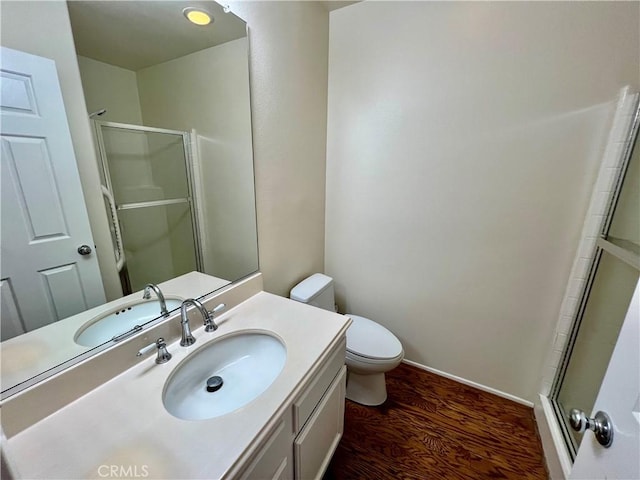 bathroom featuring wood-type flooring, toilet, vanity, and walk in shower