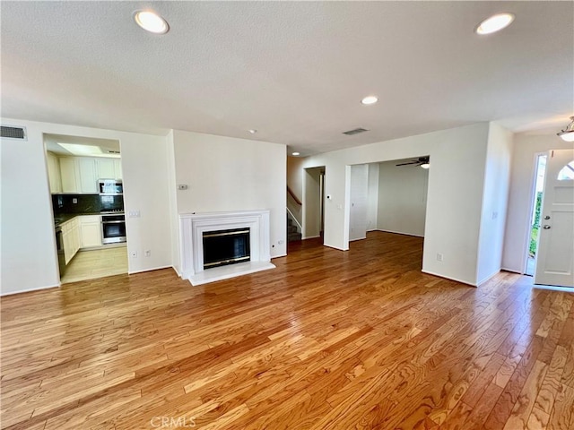 unfurnished living room featuring ceiling fan and light hardwood / wood-style floors