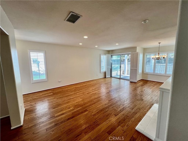 unfurnished living room with hardwood / wood-style floors and a notable chandelier