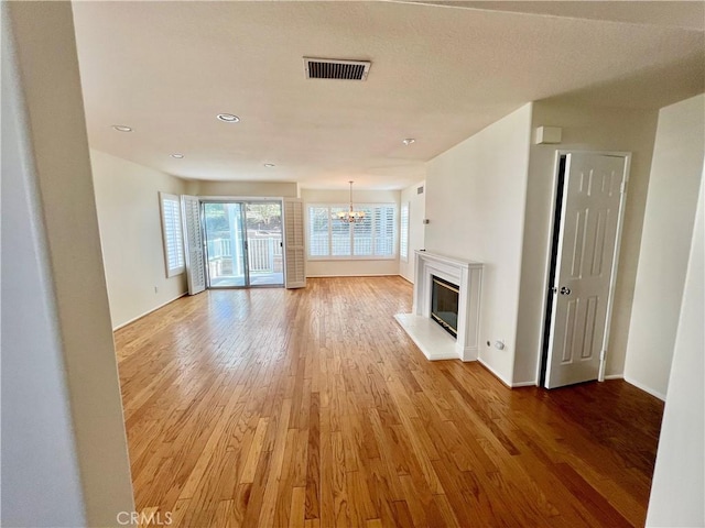 unfurnished living room with a chandelier and hardwood / wood-style floors