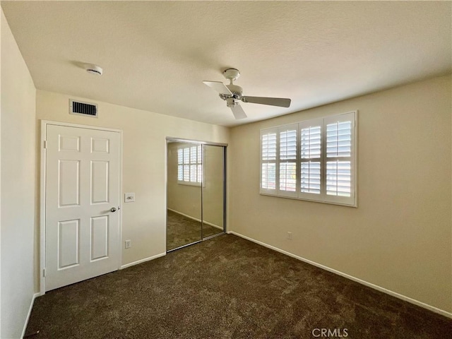 unfurnished bedroom featuring dark colored carpet, ceiling fan, and a closet