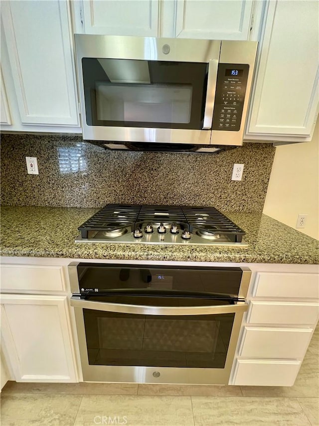 kitchen with stainless steel appliances, white cabinetry, stone counters, and backsplash