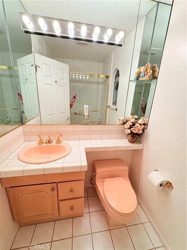 bathroom with a shower with door, vanity, tile patterned floors, and toilet