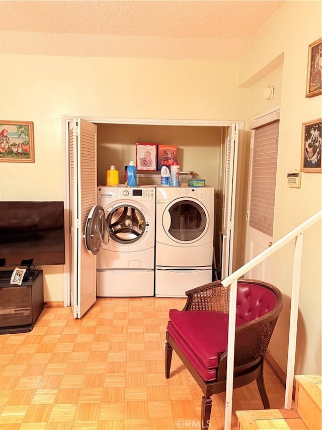 laundry room featuring washer and clothes dryer, light parquet flooring, and a textured ceiling