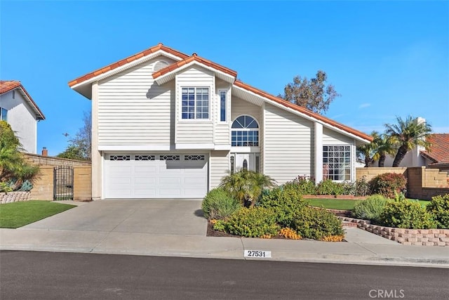 view of front of home with driveway, an attached garage, and fence