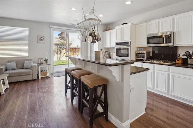 31242 Bell Mountain Rd, Menifee, CA 92584 - kitchen featuring stainless steel appliances, dark countertops, a kitchen breakfast bar, dark wood-style flooring, and recessed lighting