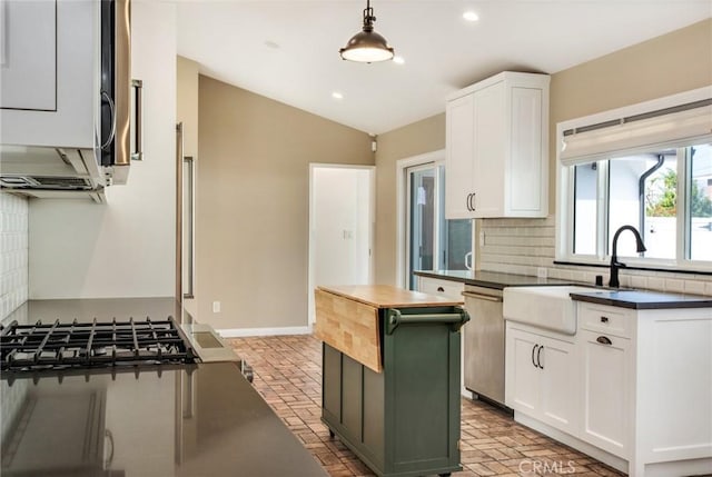 kitchen featuring decorative backsplash, dishwasher, white cabinets, and decorative light fixtures