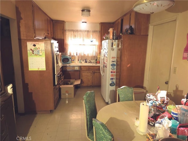 kitchen with dishwasher, stainless steel microwave, brown cabinets, freestanding refrigerator, and light countertops