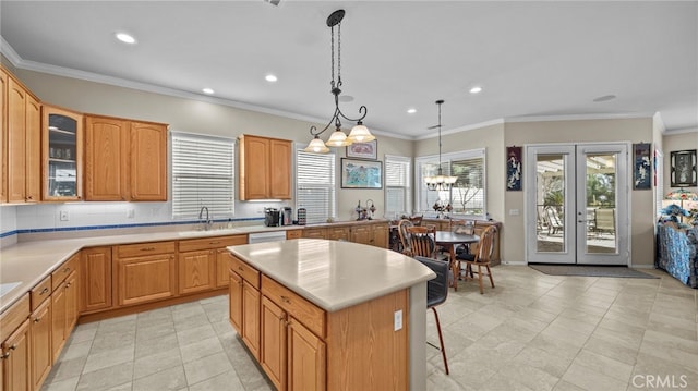 kitchen featuring hanging light fixtures, light countertops, a sink, and a center island