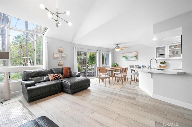 living room featuring lofted ceiling, sink, ceiling fan with notable chandelier, and light hardwood / wood-style flooring