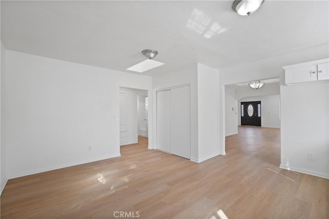 spare room featuring light hardwood / wood-style floors and a skylight