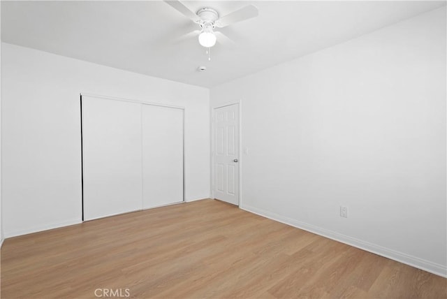 unfurnished bedroom with ceiling fan, a closet, and light wood-type flooring