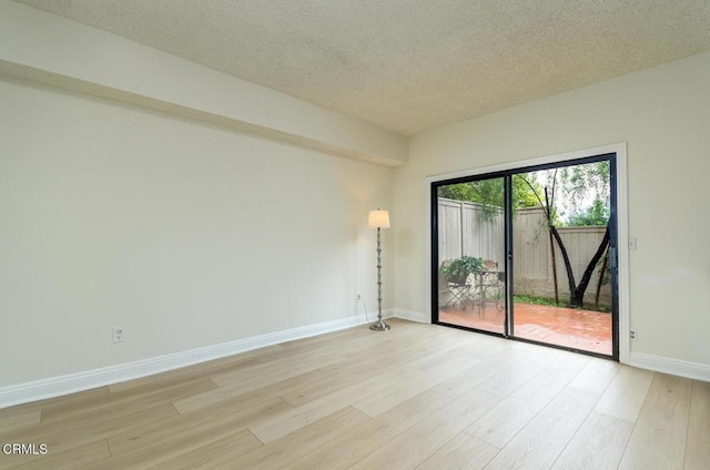 unfurnished room with light hardwood / wood-style flooring and a textured ceiling