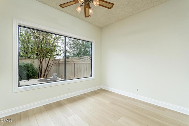 spare room featuring ceiling fan, light hardwood / wood-style flooring, and a textured ceiling