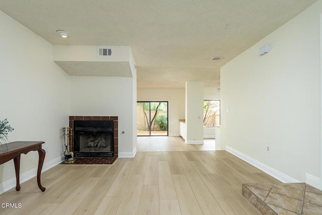 living room with a tile fireplace and light wood-type flooring