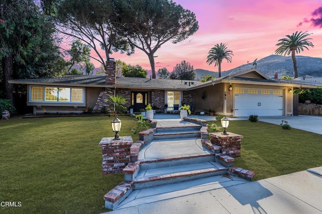 ranch-style house featuring a garage and a lawn