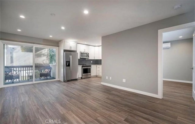 kitchen with appliances with stainless steel finishes, white cabinetry, backsplash, a wall mounted air conditioner, and dark hardwood / wood-style flooring