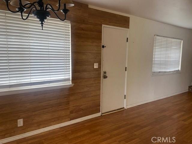 entryway featuring an inviting chandelier, dark hardwood / wood-style flooring, and wood walls