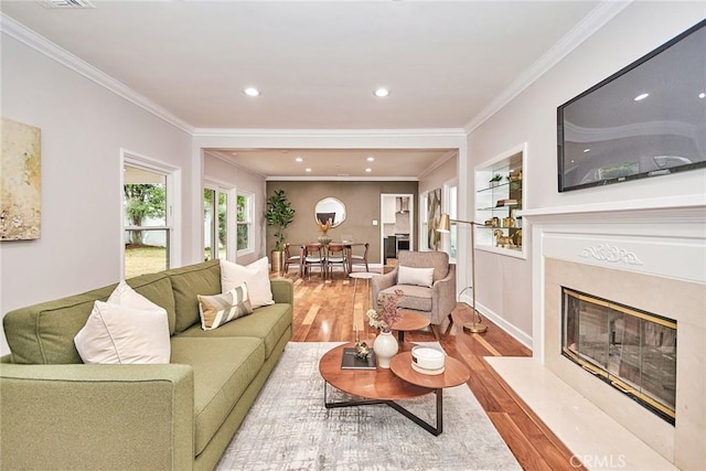 living room with crown molding, a high end fireplace, and hardwood / wood-style floors