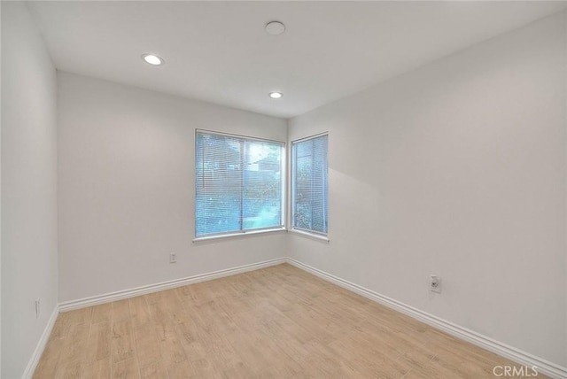 spare room featuring light wood-style floors, baseboards, and recessed lighting