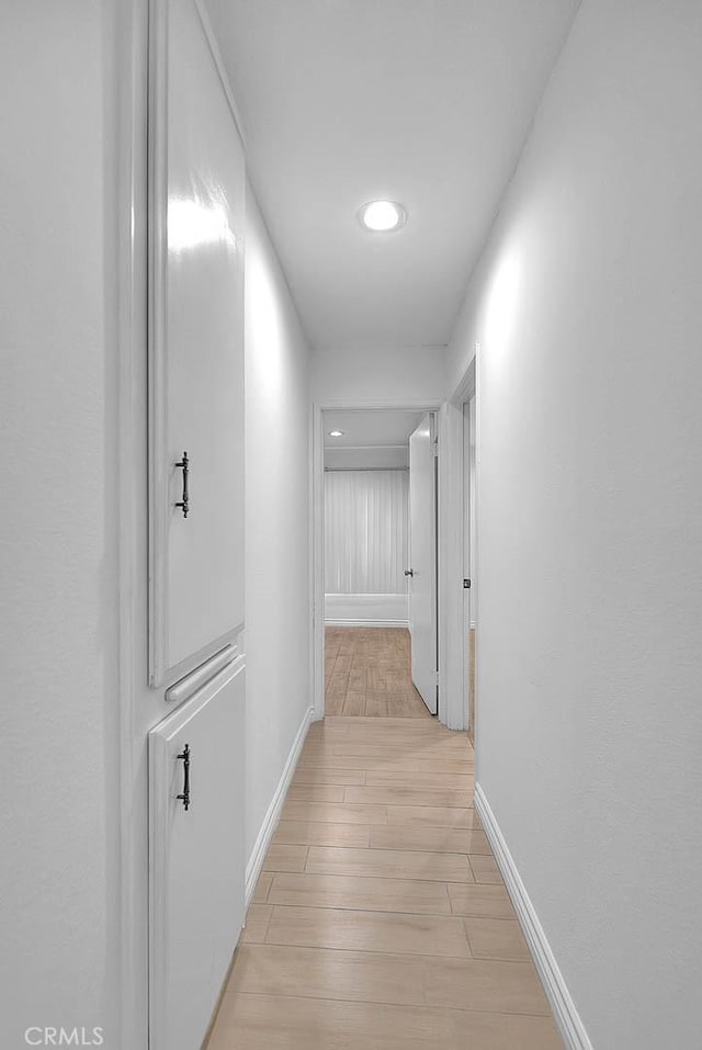 hall featuring baseboards and light wood-style floors