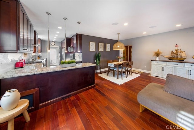 kitchen featuring light stone counters, dark hardwood / wood-style floors, pendant lighting, stainless steel appliances, and backsplash