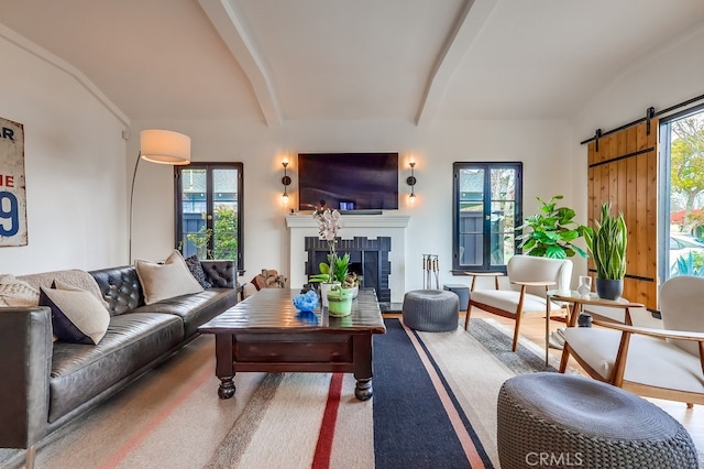 living room featuring a barn door, plenty of natural light, and vaulted ceiling with beams