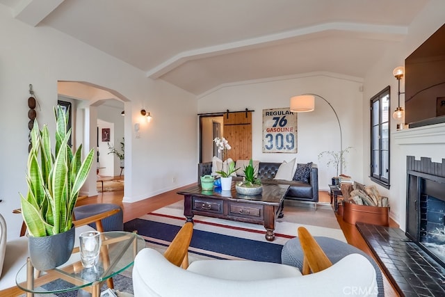 living room with wood-type flooring, a barn door, and vaulted ceiling