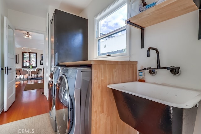 washroom with separate washer and dryer, sink, and hardwood / wood-style flooring