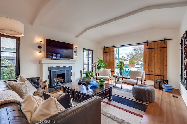 living room with a barn door, hardwood / wood-style floors, and vaulted ceiling with beams