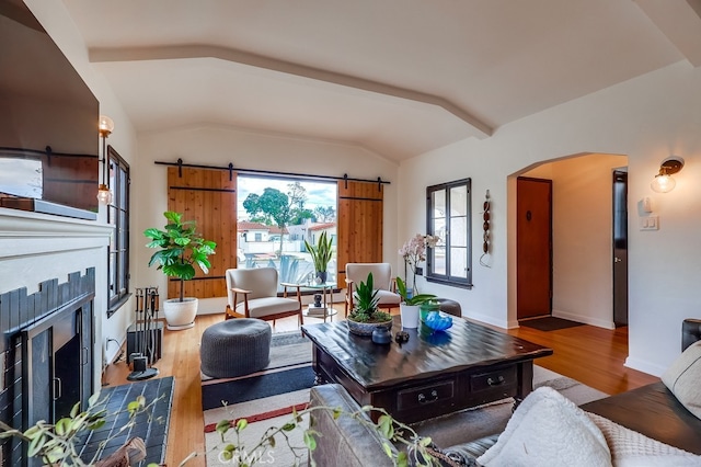 living room with vaulted ceiling, a barn door, and hardwood / wood-style floors