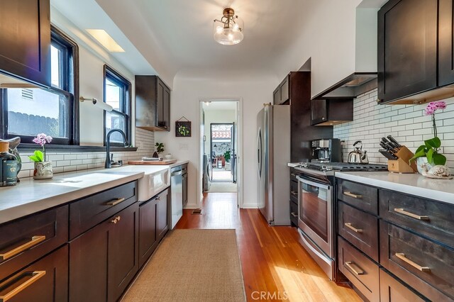 kitchen featuring dark brown cabinetry, sink, custom exhaust hood, and appliances with stainless steel finishes