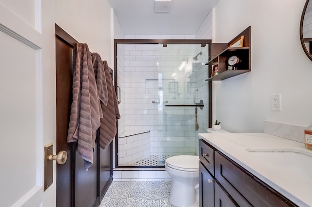 bathroom featuring a shower with door, vanity, tile patterned floors, and toilet