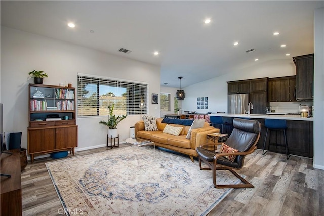 living room with wood-type flooring, sink, and vaulted ceiling