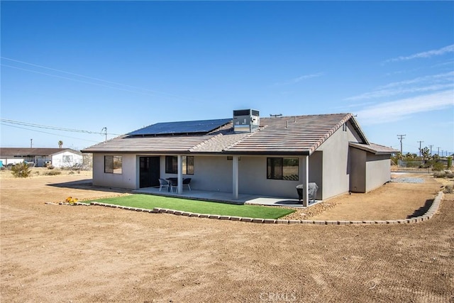 back of property with central air condition unit, a patio, and solar panels