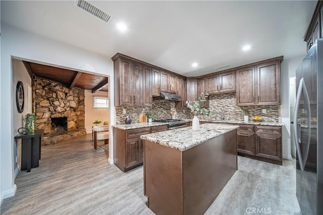 kitchen with tasteful backsplash, dark brown cabinetry, stainless steel appliances, and a center island