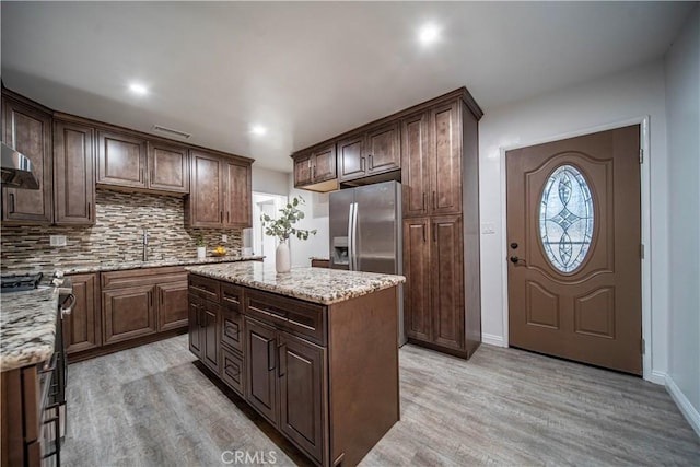 kitchen featuring dark brown cabinetry, light hardwood / wood-style floors, appliances with stainless steel finishes, and a kitchen island