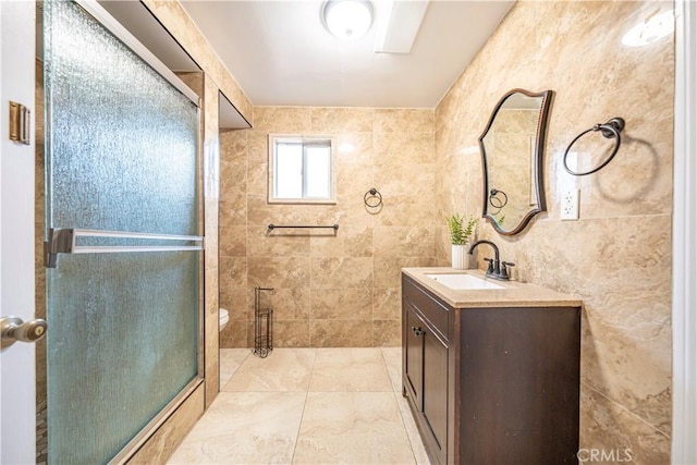 bathroom featuring vanity, toilet, an enclosed shower, and tile walls