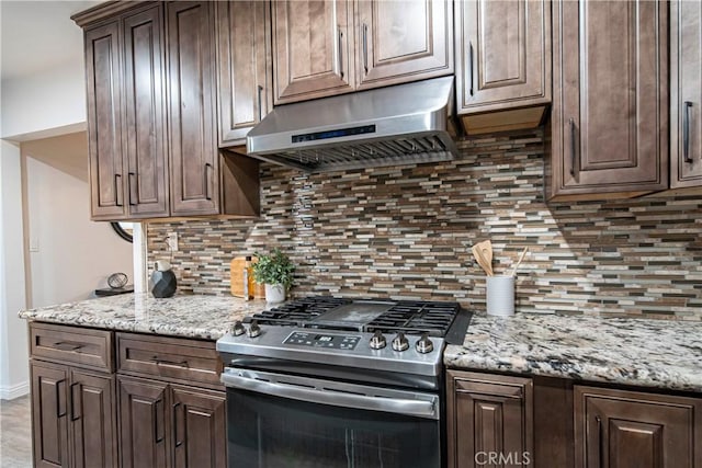 kitchen featuring dark brown cabinetry, stainless steel range with gas cooktop, light stone countertops, and backsplash